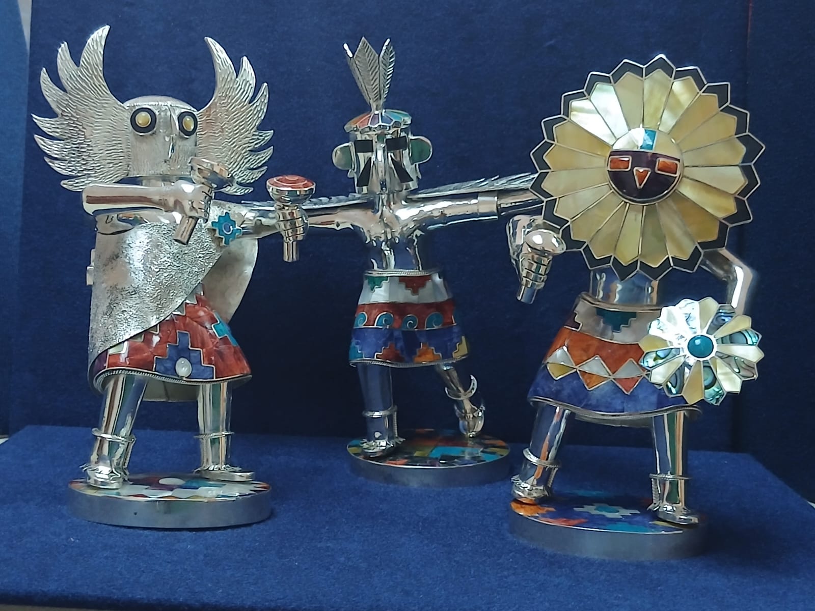 Three silver Inca inspired figures on blue backdrop